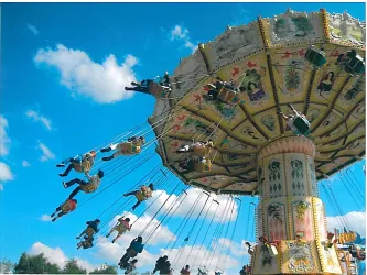 Ein aufregendes Karussell mit schwingenden Sitzen unter einem klaren blauen Himmel. Menschen genießen die Fahrt und haben Spaß.