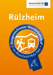 Ein Siegel für den Wanderbahnhof Rülzheim im Rheinland-Pfalz-Takt. Die Auszeichnung stammt aus dem Jahr 2012 und hebt die Bedeutung des Bahnhofs für Wanderer hervor.