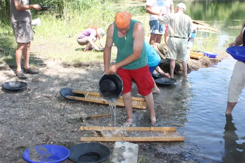 Goldwäscher mit Eimer und Waschbrett beim Goldwaschen