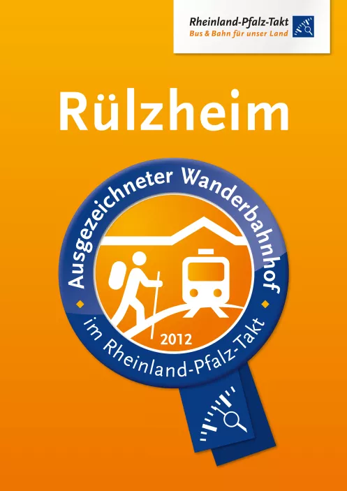 Logo Wanderbahnhof zeigt auf orangefarbenm Hintergrund in blauem Kreis Wanderer und Bahn