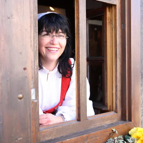 Frau in Tracht schaut aus dem Fenster